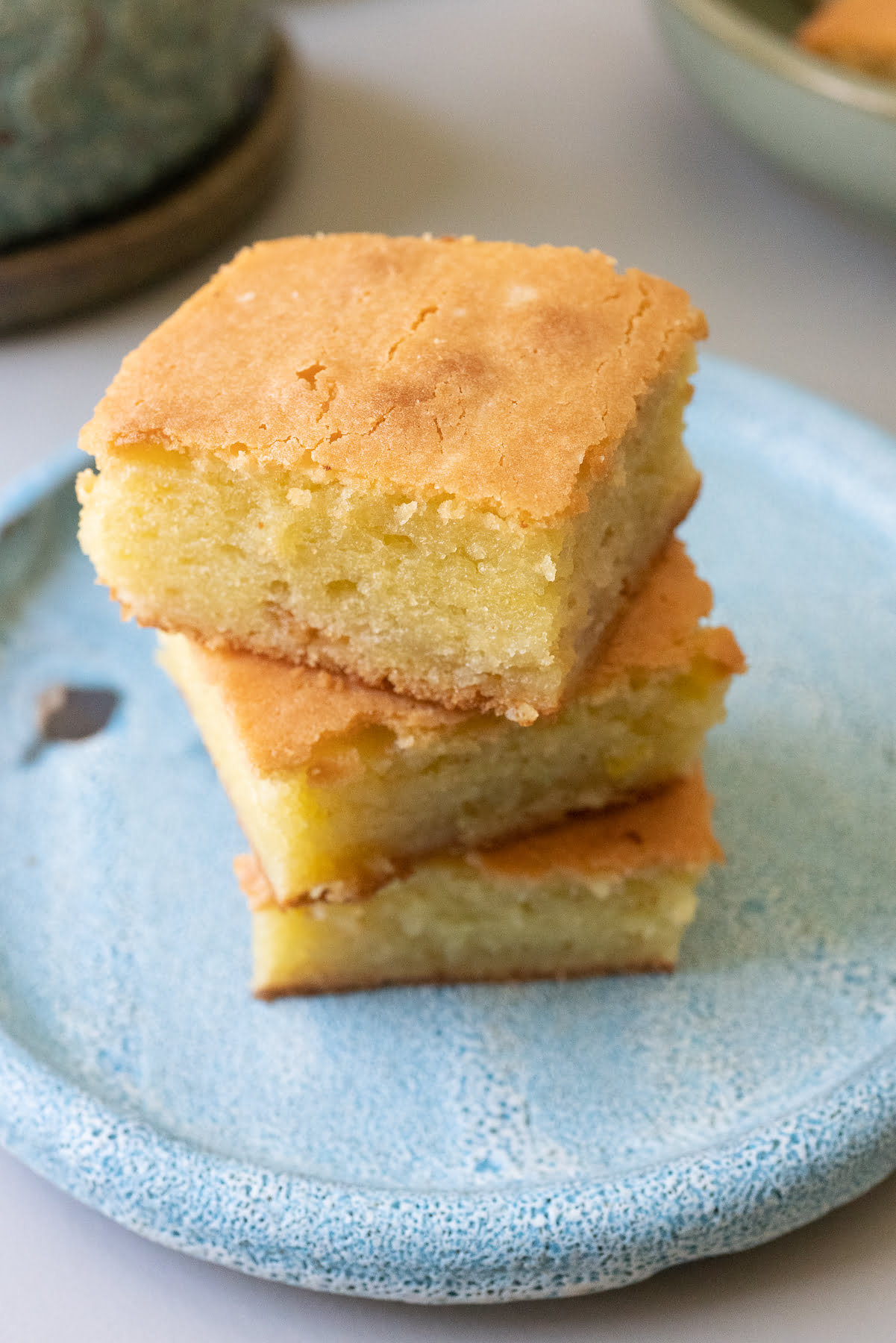 A stack of butter mochi squares on a plate.