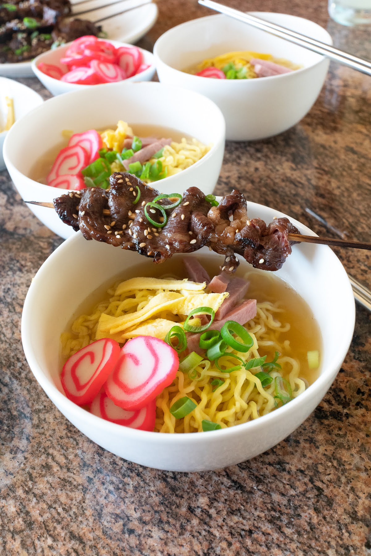 A bowl of saimin with a teri beef stick on top.