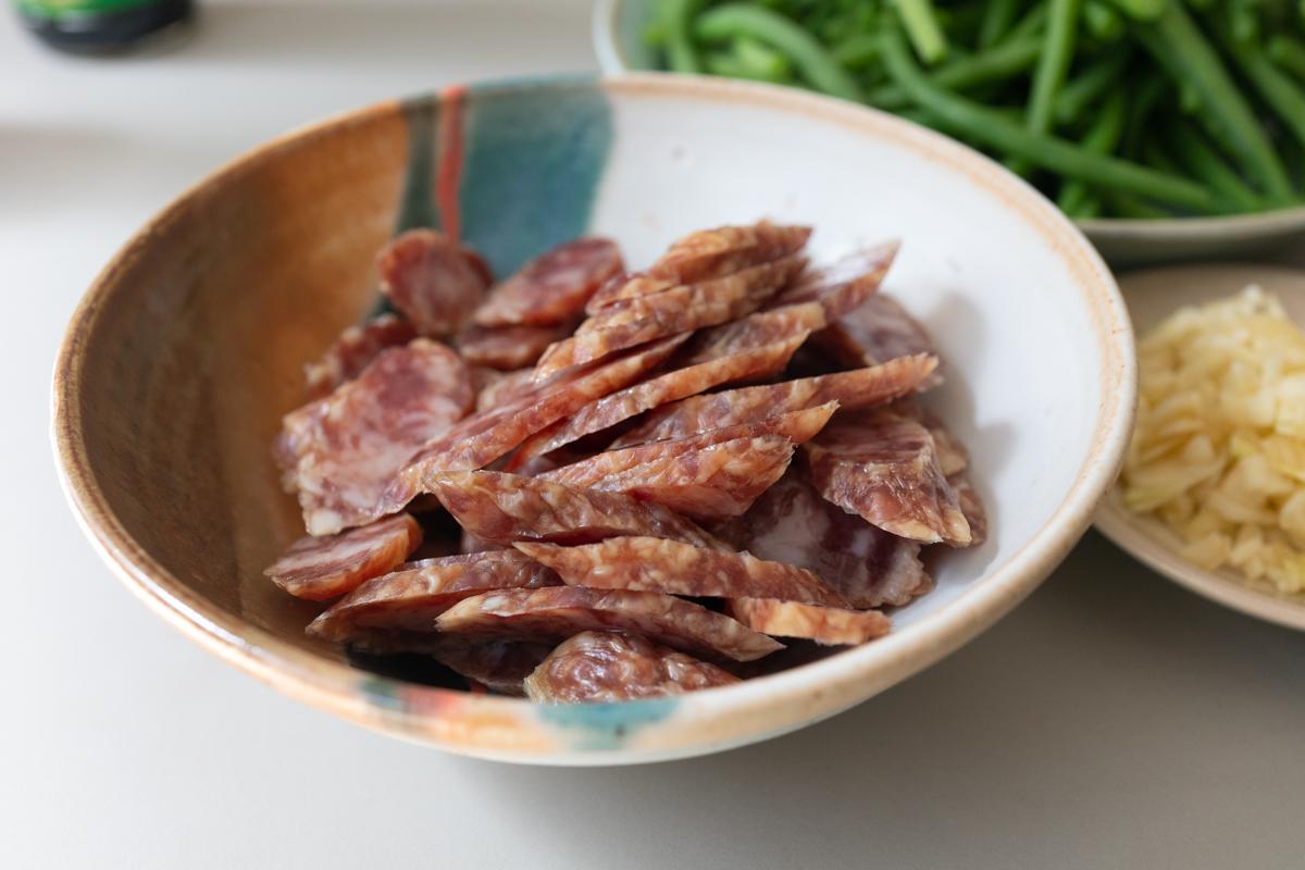 Chinese sausage, sliced, in a bowl and ready for cooking