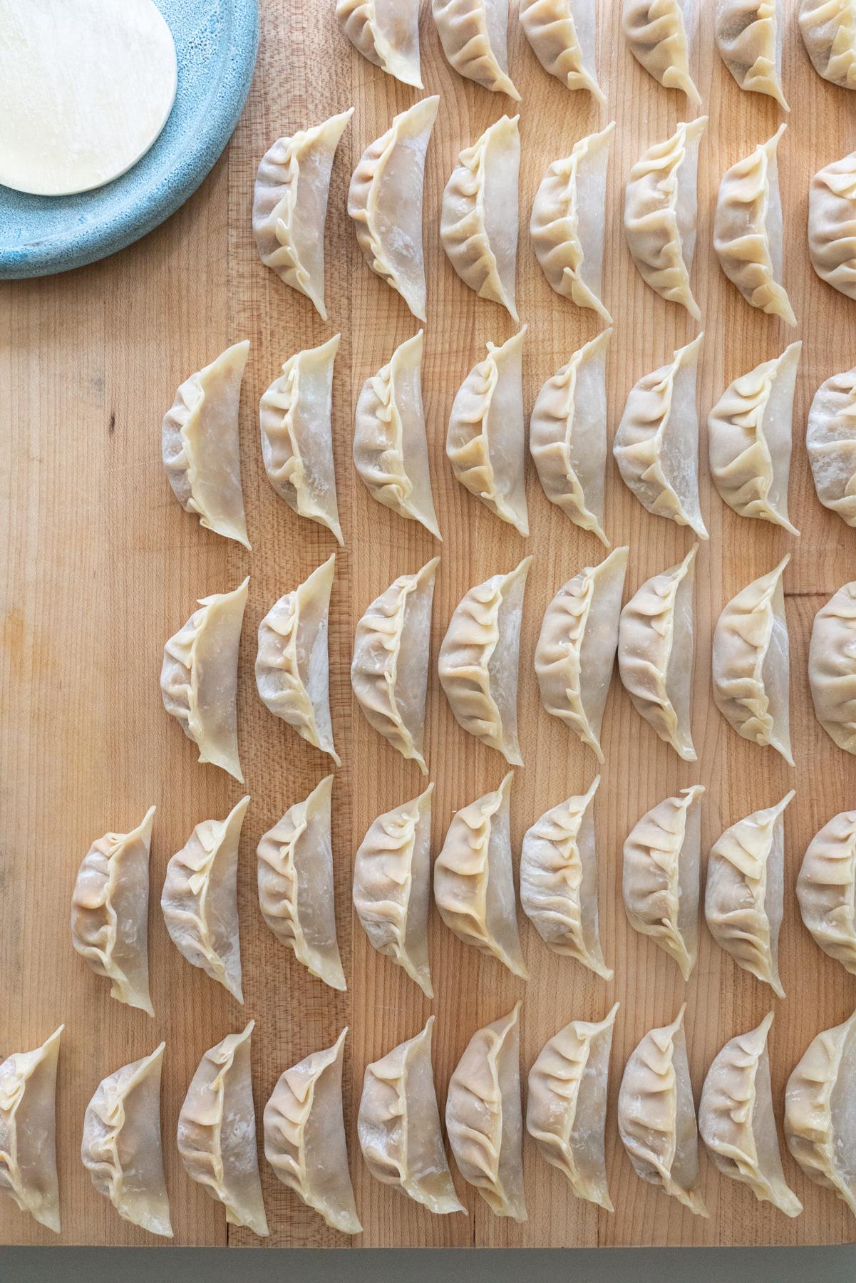wrapped kimchi dumplings all lined up on a cutting board