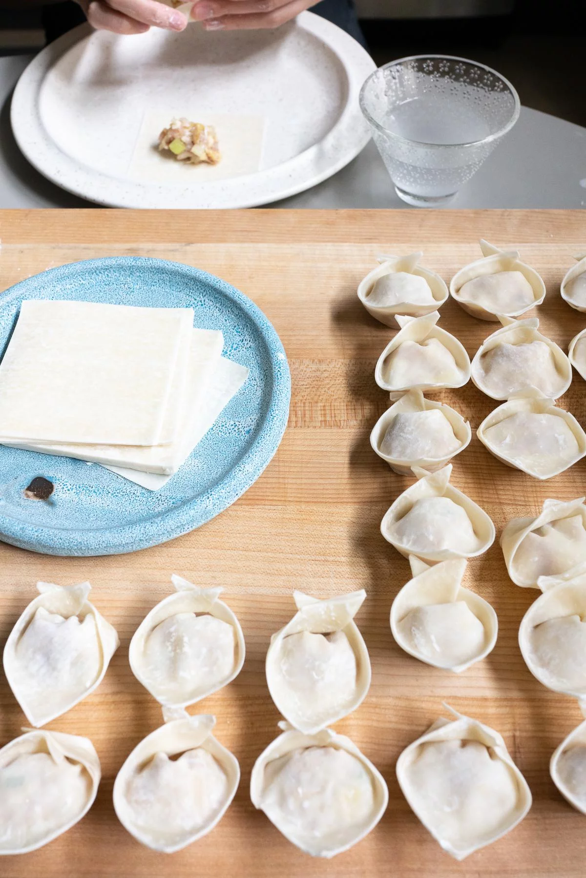 A cutting board filled with wrapped wontons