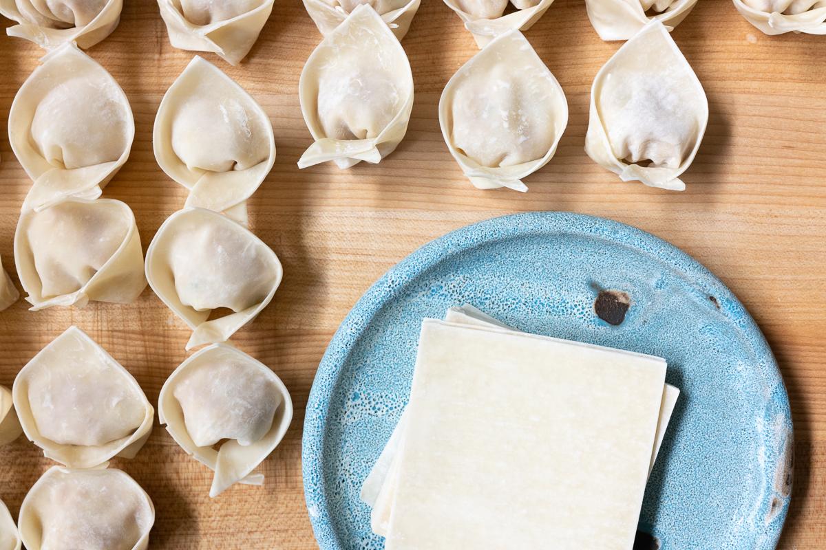 A cutting board filled with wrapped wontons