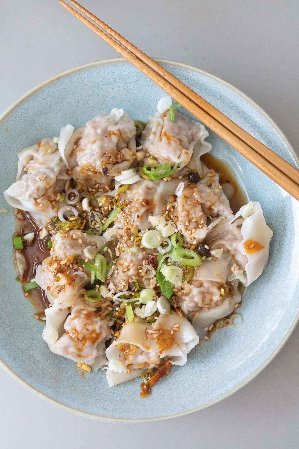 A plate of boiled wontons with wonton dipping sauce poured over
