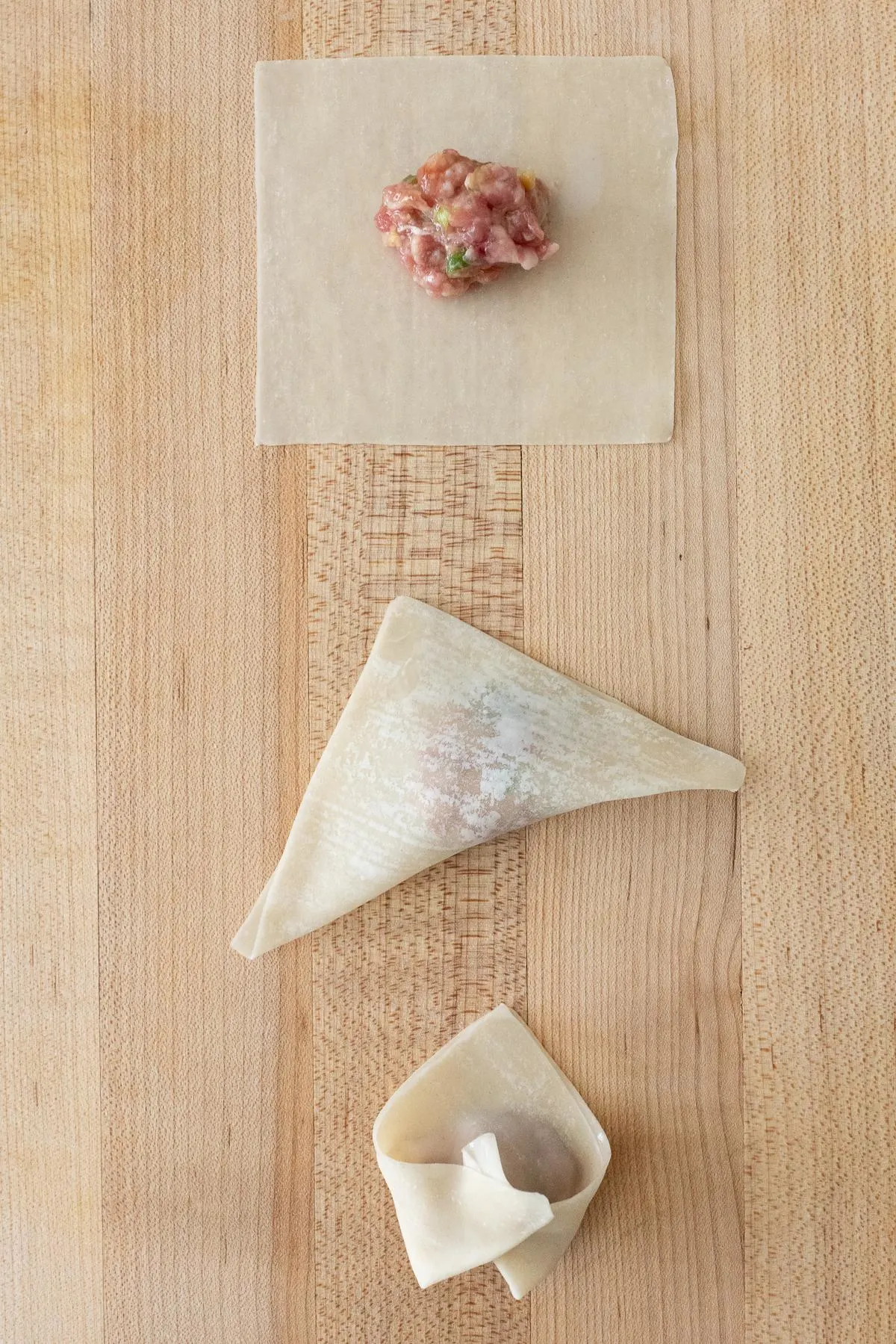 Three steps to folding pork wontons. Place filling in center, fold a triangle, bring the corners together and seal.