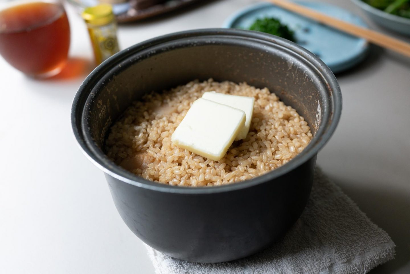 Adding butter to the scallop and rice in the rice cooker pot