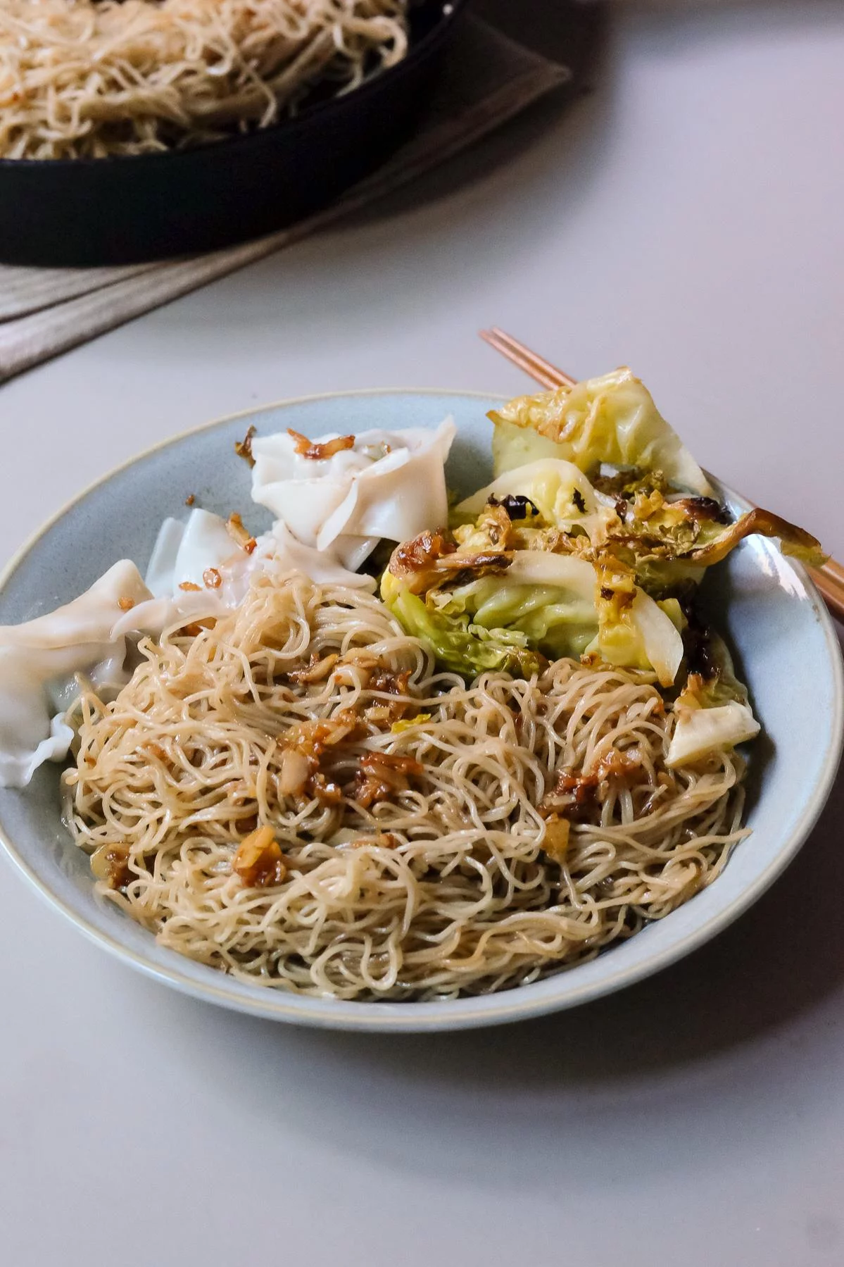 A plate of Gon Lo Mein with boiled wontons and roasted cabbage, ready to eat.