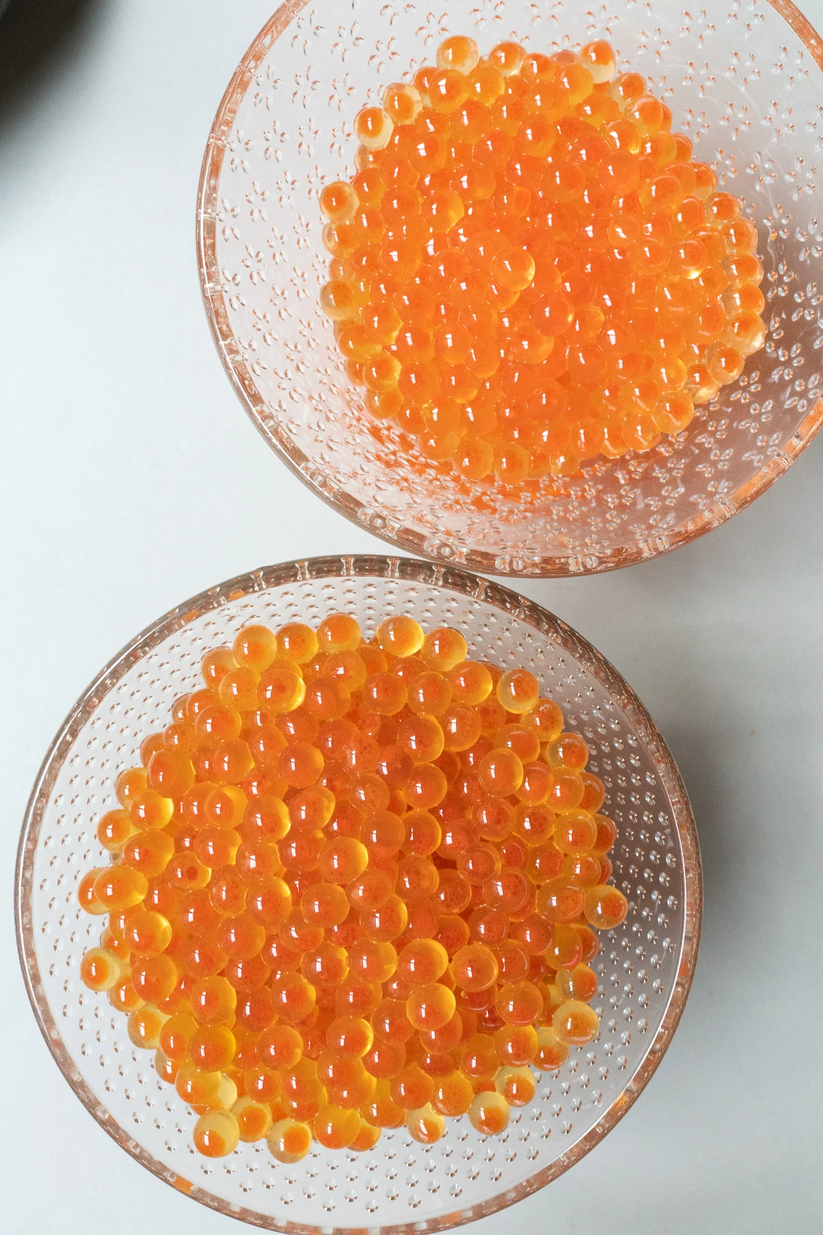 Two small glass bowls, one with salt-cured salmon roe, another with soy sauce-cured salmon roe.