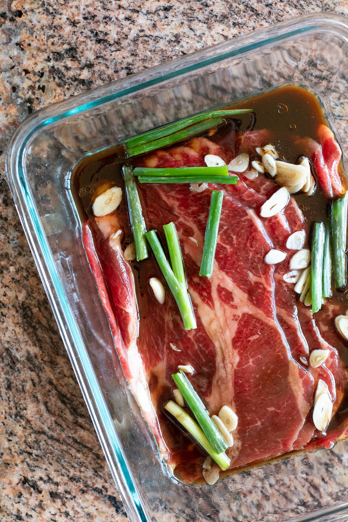 Marinating the rib eye slices in a mixture of soy sauce, sesame oil, sugar, garlic, and green onions.