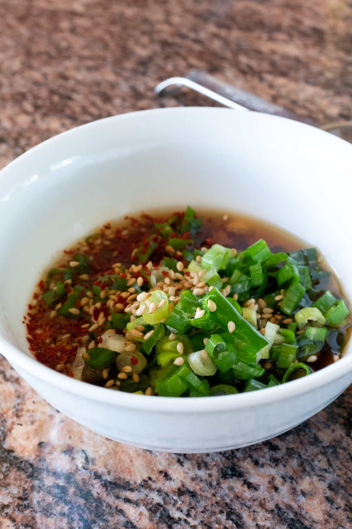 Meat jun dipping sauce made from soy sauce, rice vinegar, sesame oil, Korean chili pepper flakes (optional), garlic cloves, and green onions.
