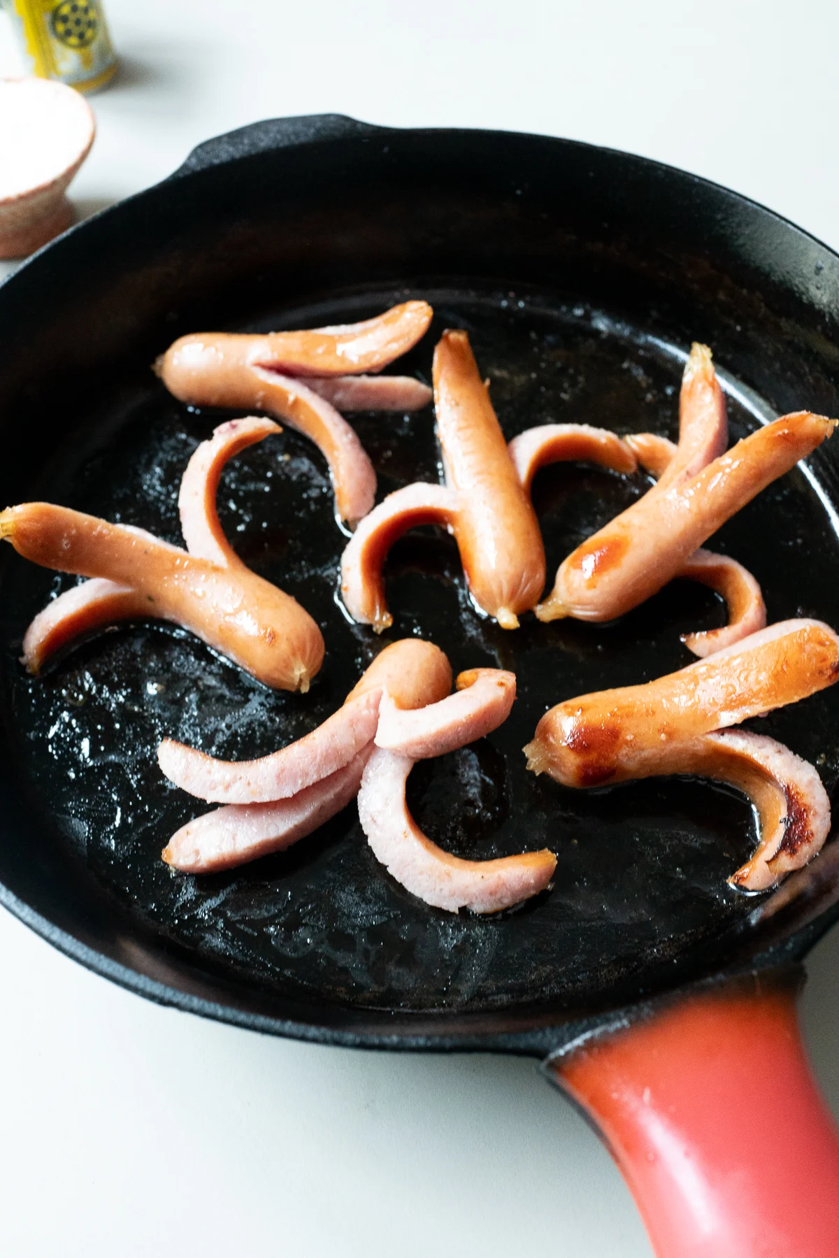 Six cooked Octopus Hot Dogs in a cast iron pan.