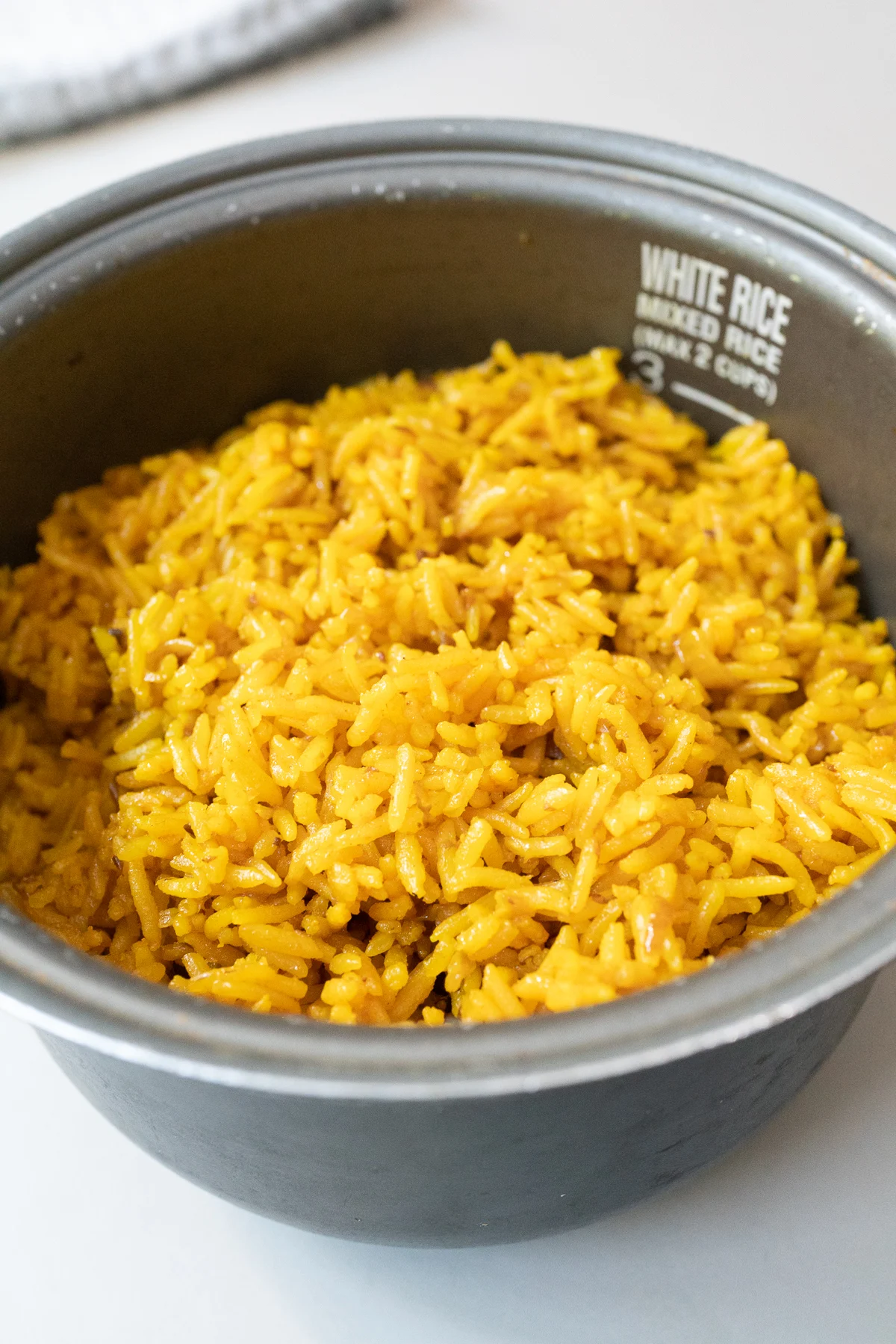 A rice cooker pot filled with freshly cooked turmeric rice.