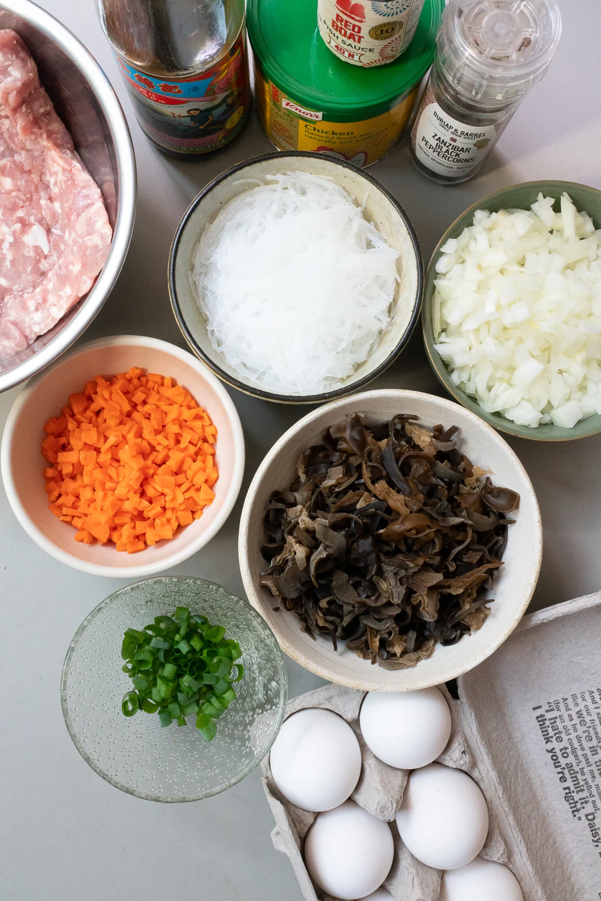 Ingredients for Vietnamese Egg Meatloaf (Cha Trung): ground pork, mung bean noodles, wood ear mushrooms, eggs, carrots, onions, green onions, fish sauce, oyster sauce, chicken bouillon powder, and black pepper.