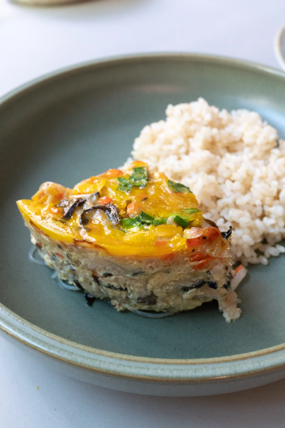 Wedge of baked Vietnamese Egg Meatloaf (Cha Trung) served with rice.