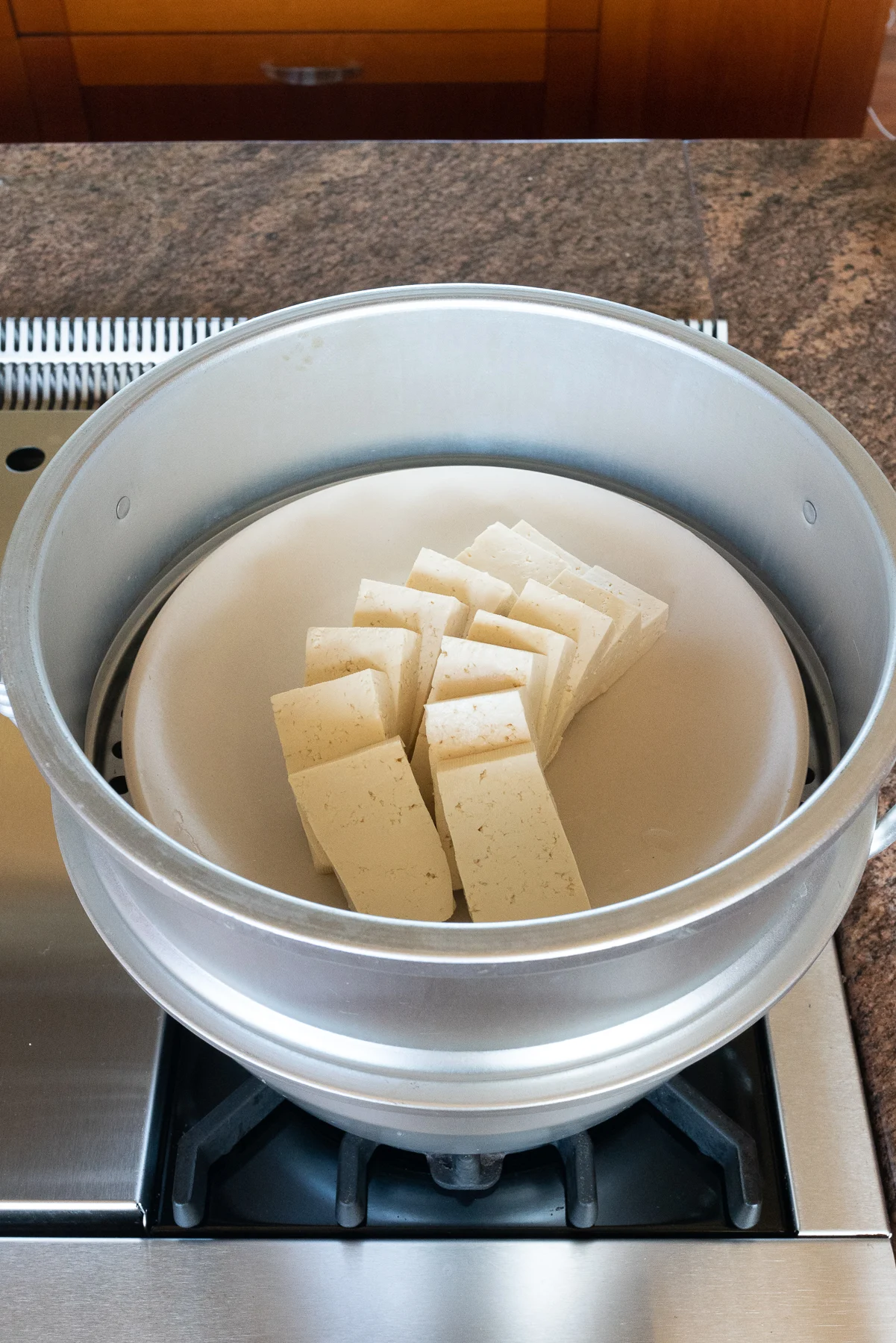 A plate of sliced tofu in the steamer, getting ready to steam.