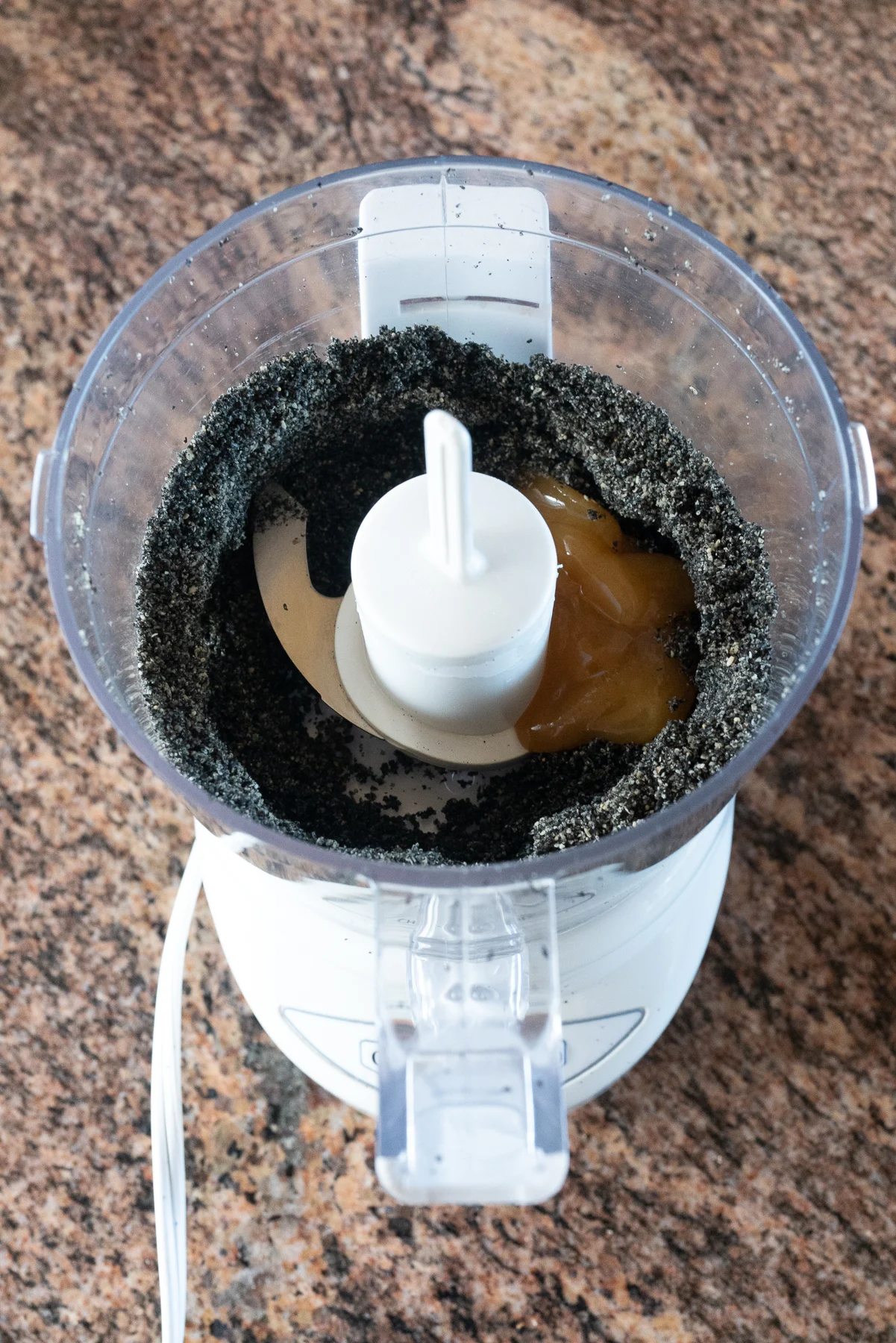 Adding honey to the toasted, roasted black sesame seeds in the food processor.