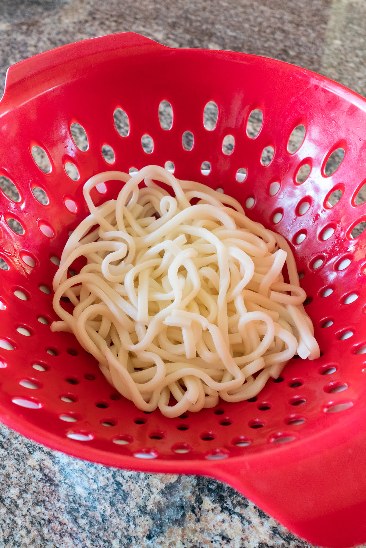 Fresh udon noodles in a colander.
