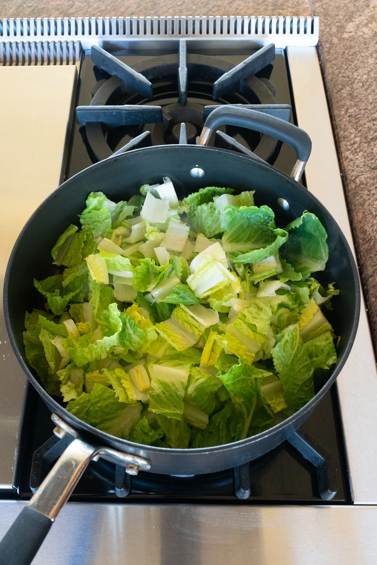 Sautéing lettuce in a pan.