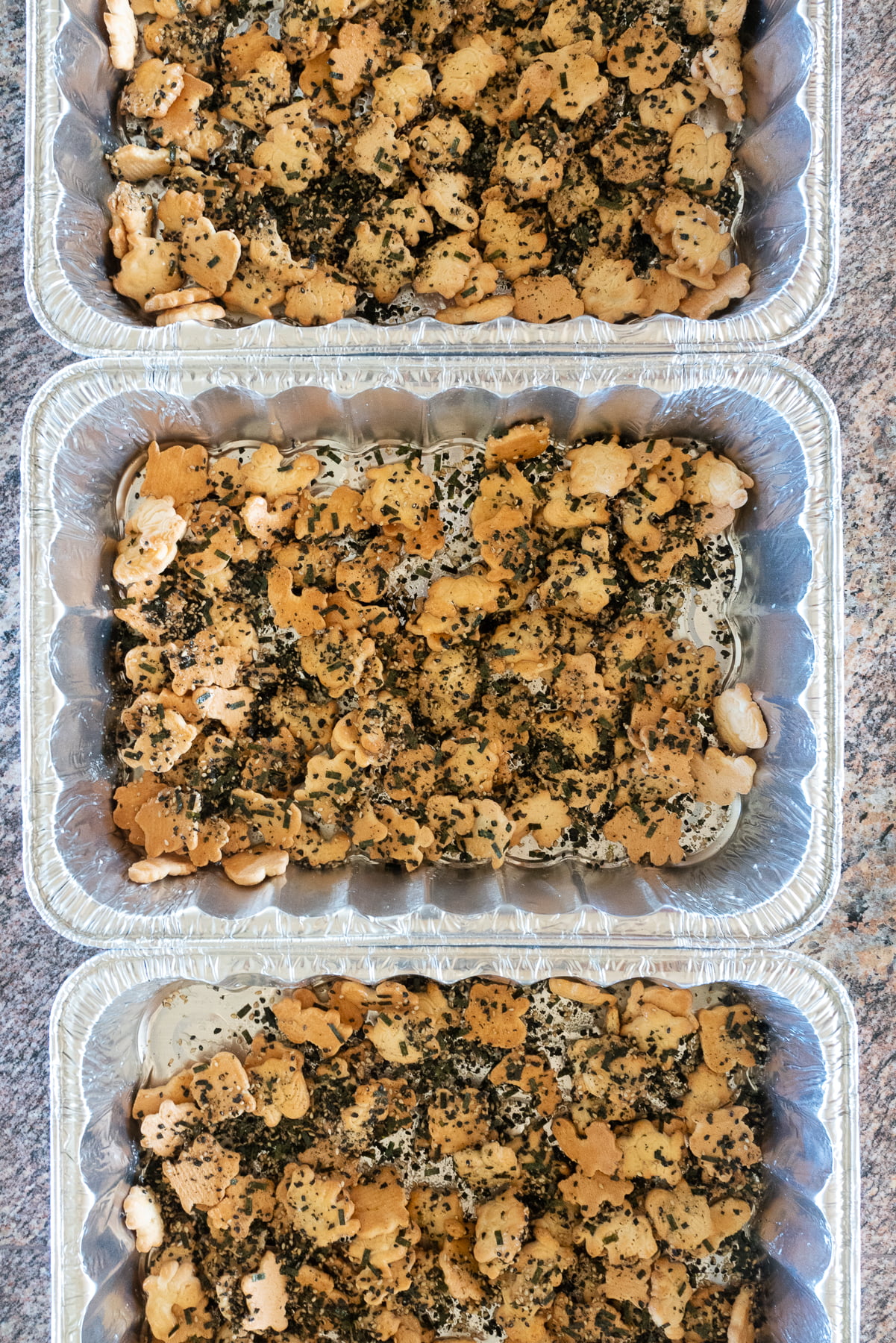 Three trays of animal crackers tossed with syrup mixture and furikake.