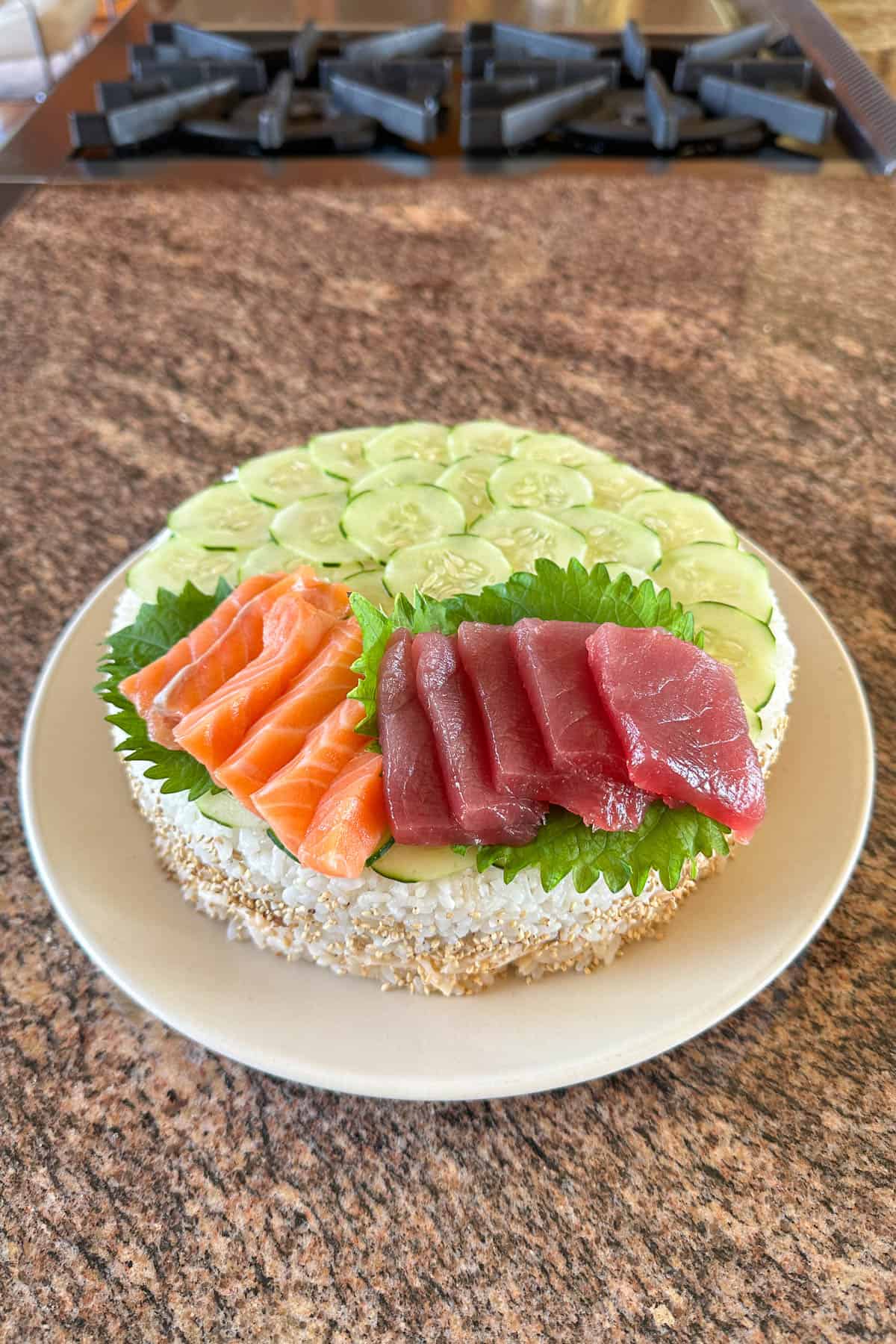 Adding sashimi to the sushi cake.