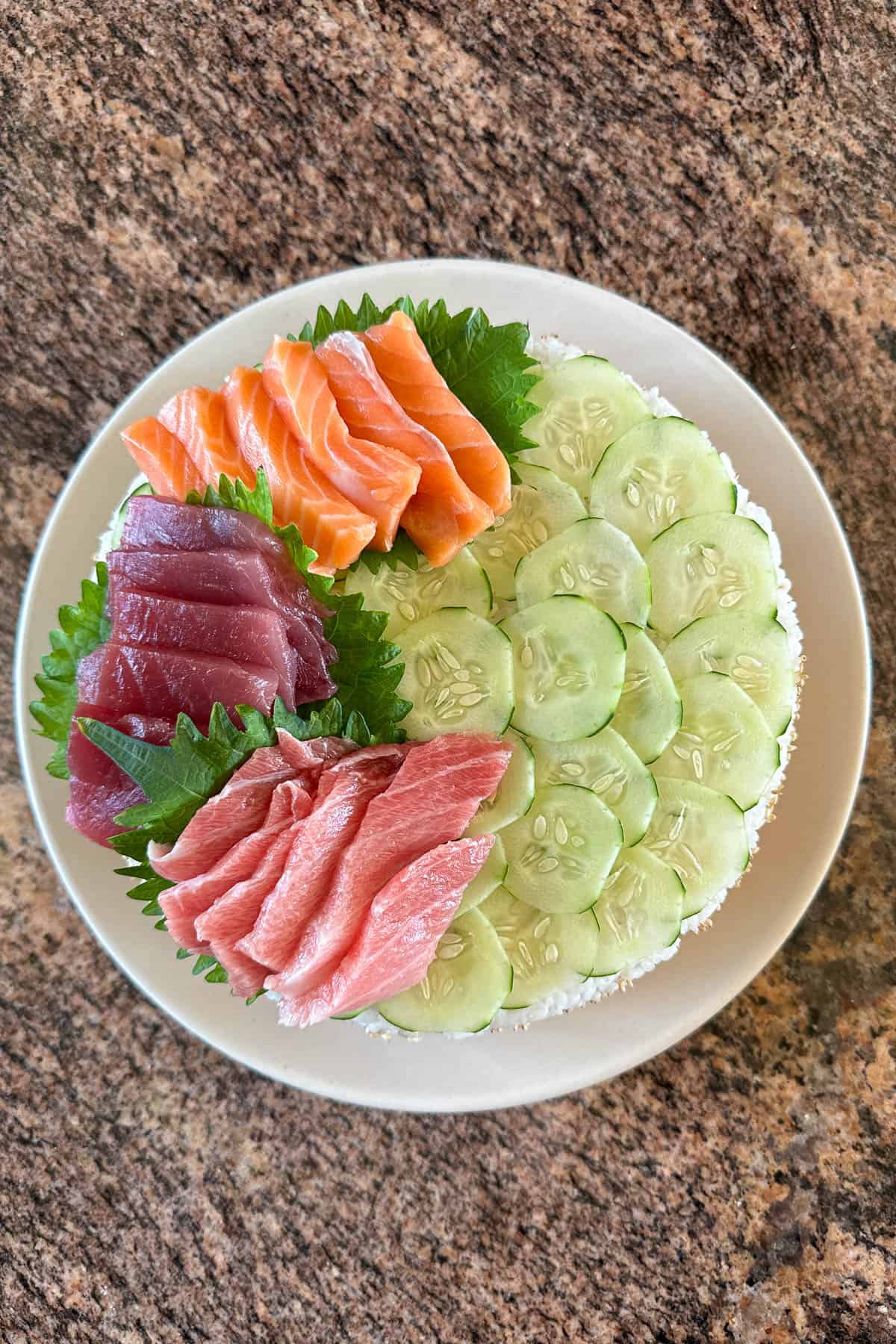 Adding sashimi to the sushi cake.