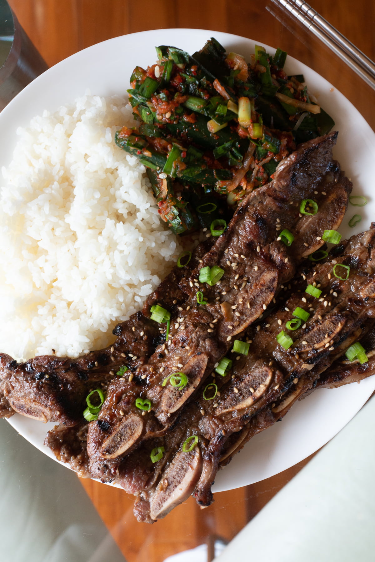 A plate of kalbi with rice and kimchi.