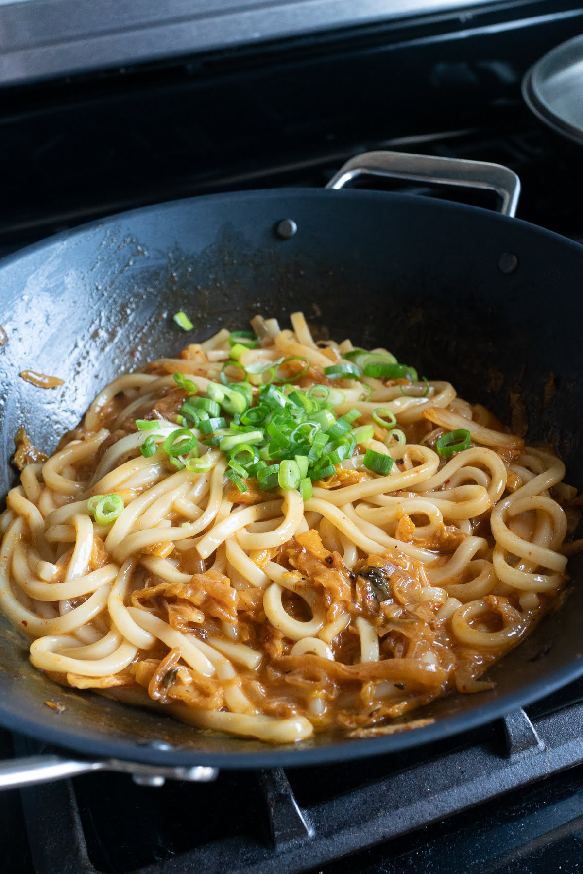 Cooking the kimchi udon with cheese in a pan.