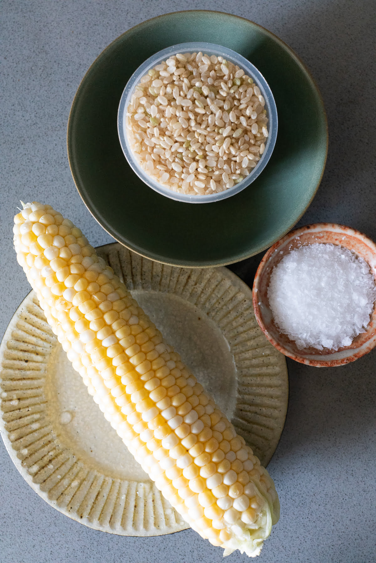 Ingredients for corn rice on a table (corn, rice, and salt).