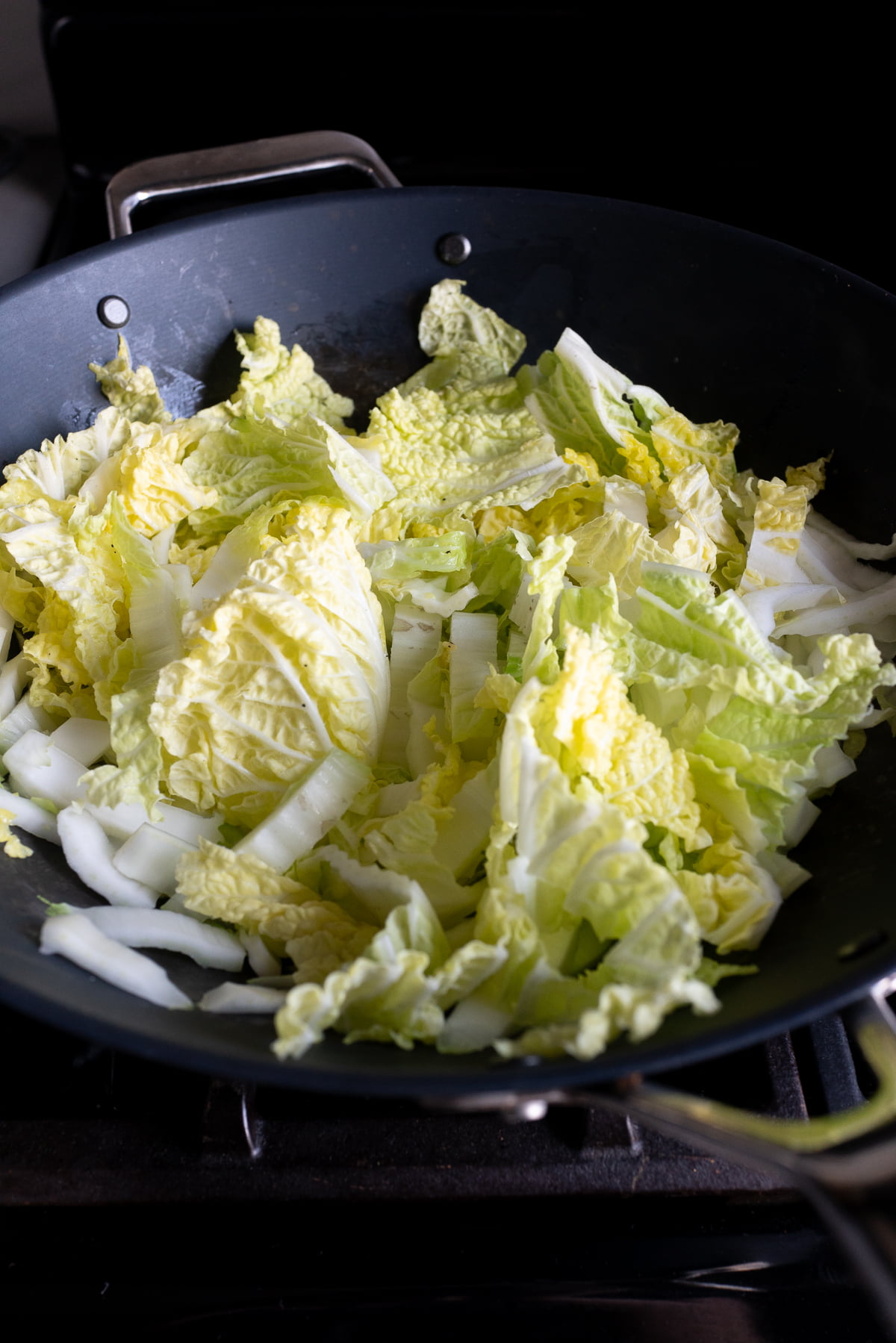 Cooking the napa cabbage for the Glass Noodles and Cabbage Stir Fry dish in a wok.