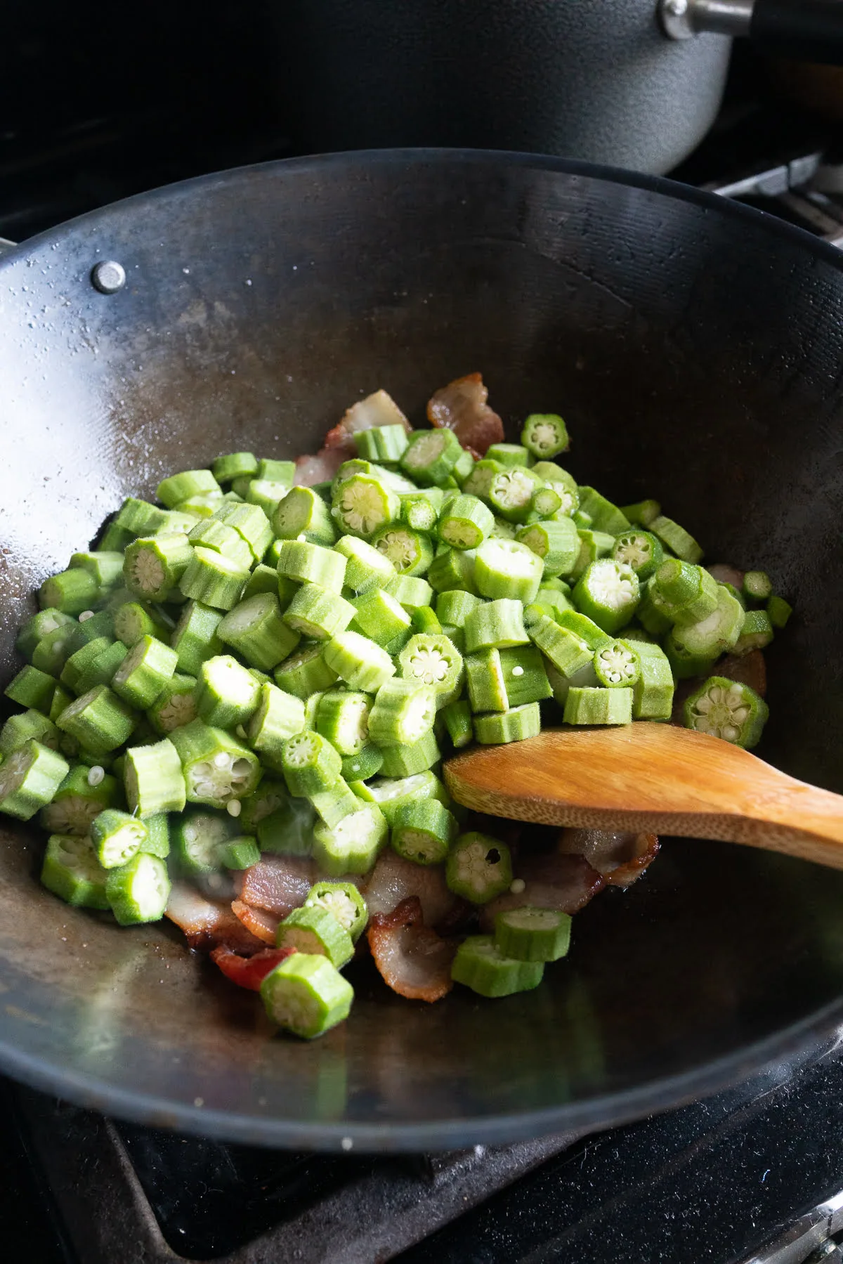 stir frying okra and bacon in a wok.