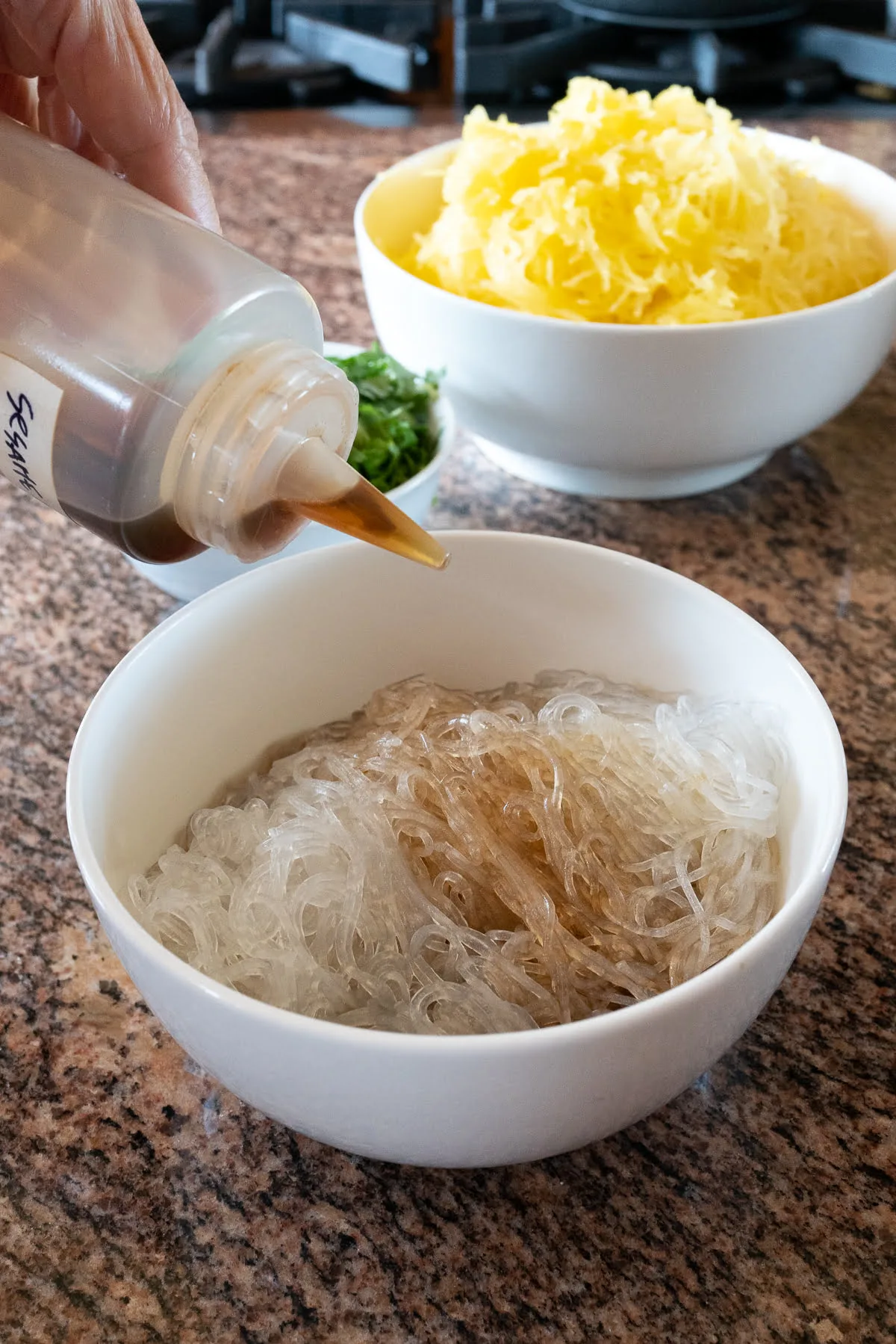 Seasoning the glass noodles with sesame oi.