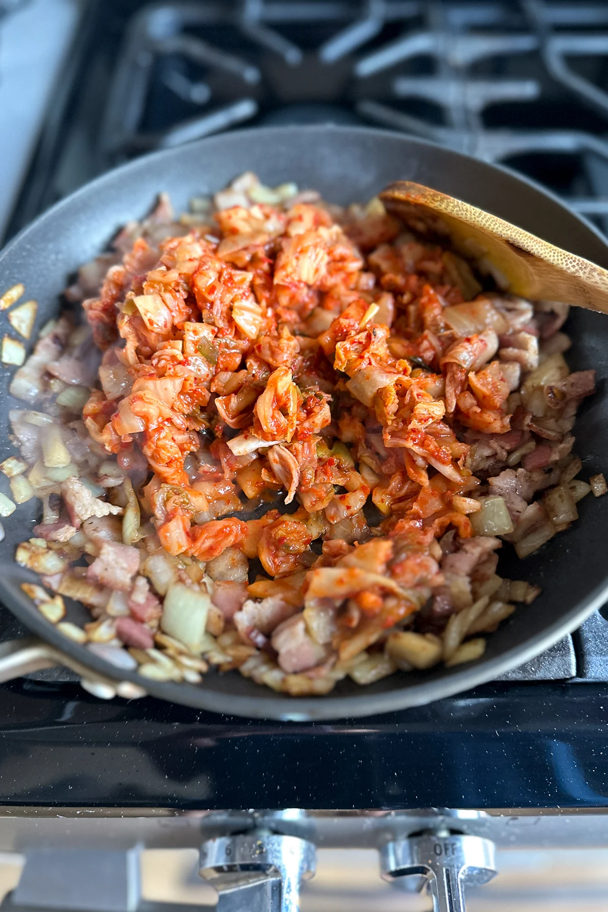 Cooking onions, bacon, and kimchi to make kimchi fried rice.