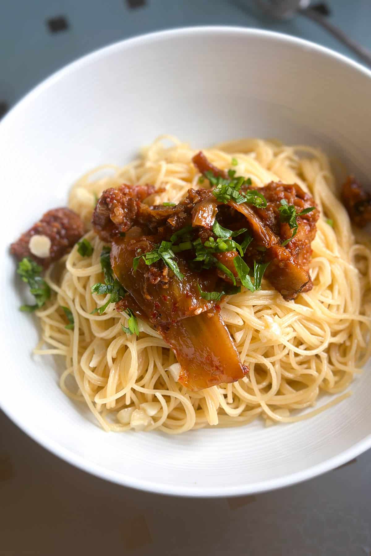 A bowl of butter soy sauce pasta topped with kimchi tofu.