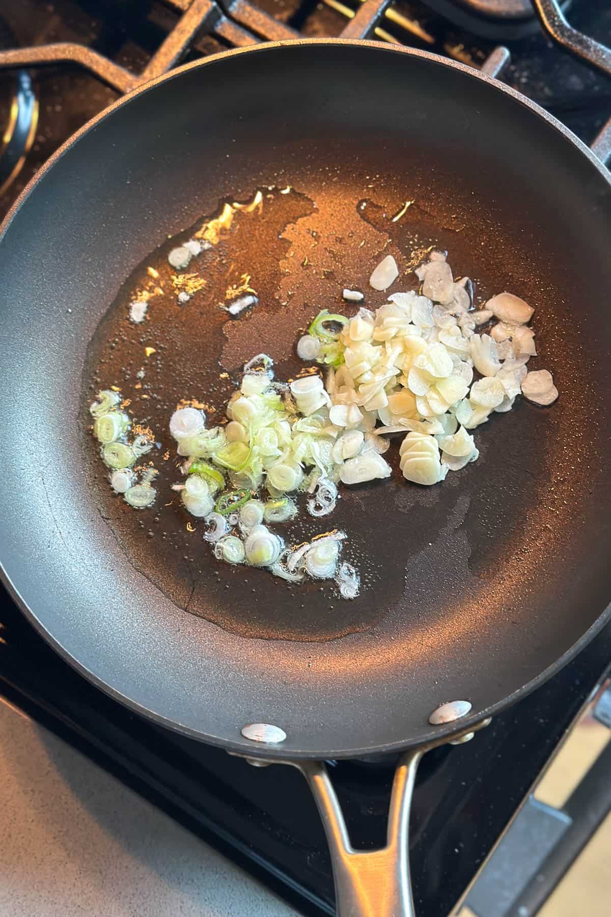Cooking garlic and green onions in a saucepan.