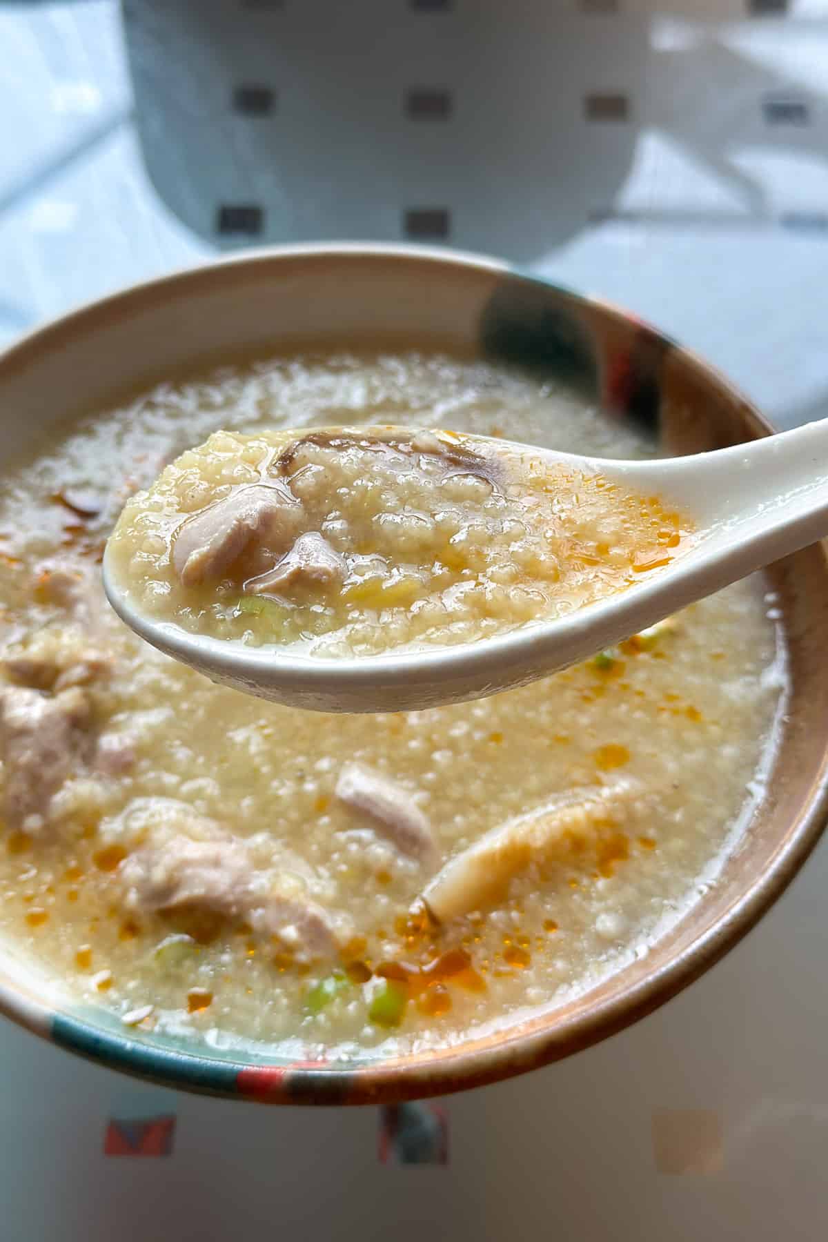 A bowl of millet porridge with chicken and mushrooms.