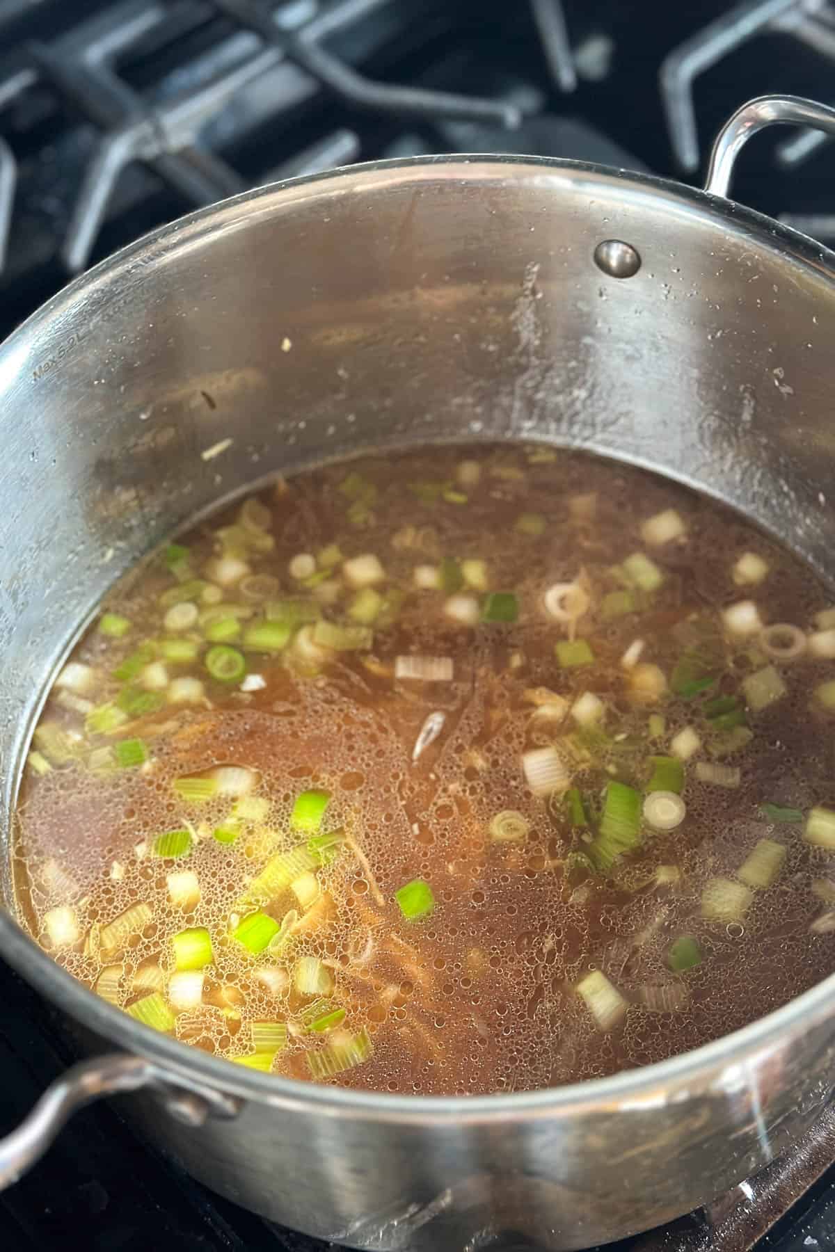 Adding the liquids to the the ginger, garlic, and green onions in a pot.