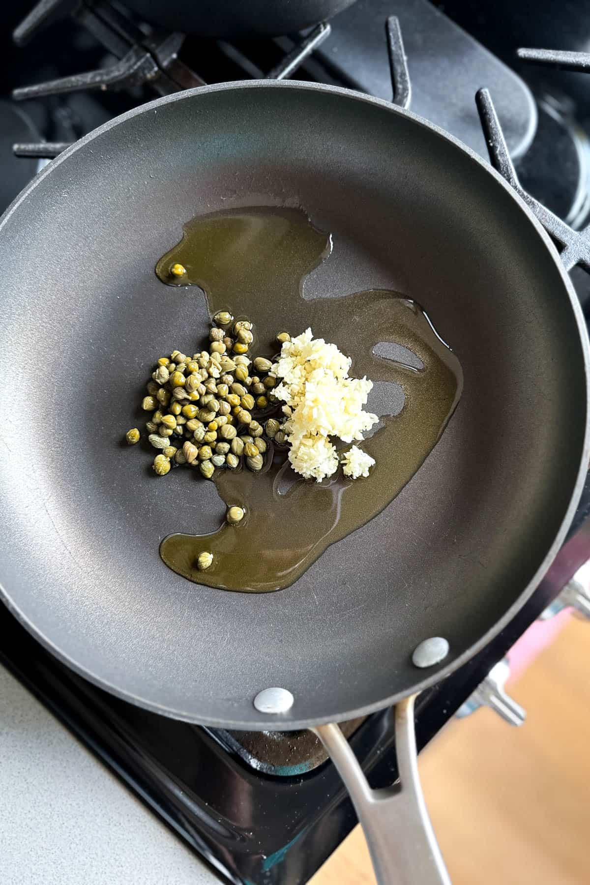 Cooking garlic and capers in olive oil for parsley pasta.