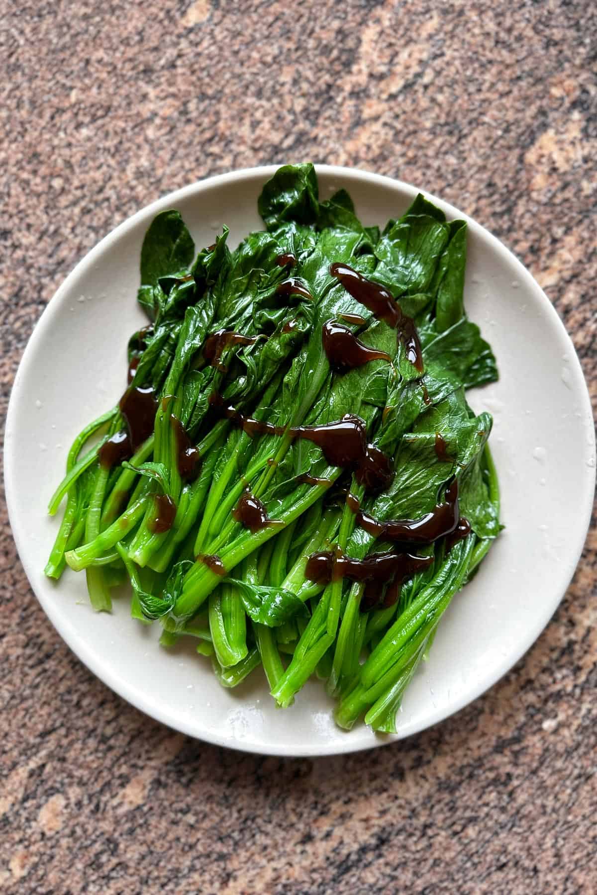 Choy sum, plated and ready to serve with a drizzle of oyster sauce.
