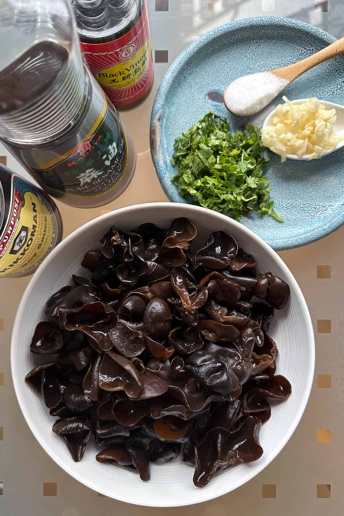 Ingredients for Wood Ear Mushroom Salad on a table (wood ear msuhrooms, garlic, black vinegar, soy sauce, sesame oil, soy sauce, and cilantro).