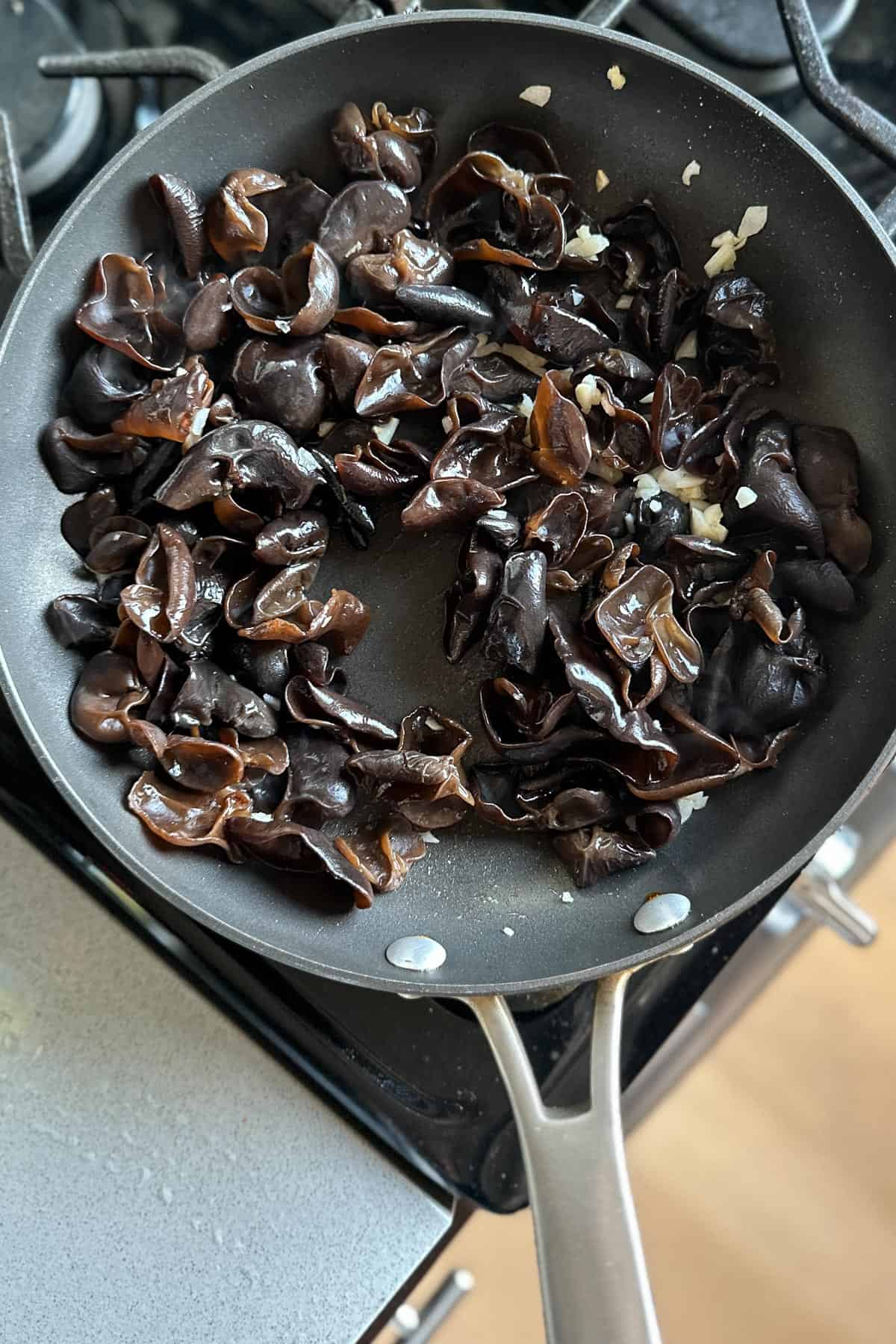 Adding wood ear mushrooms to the garlic in a pan.