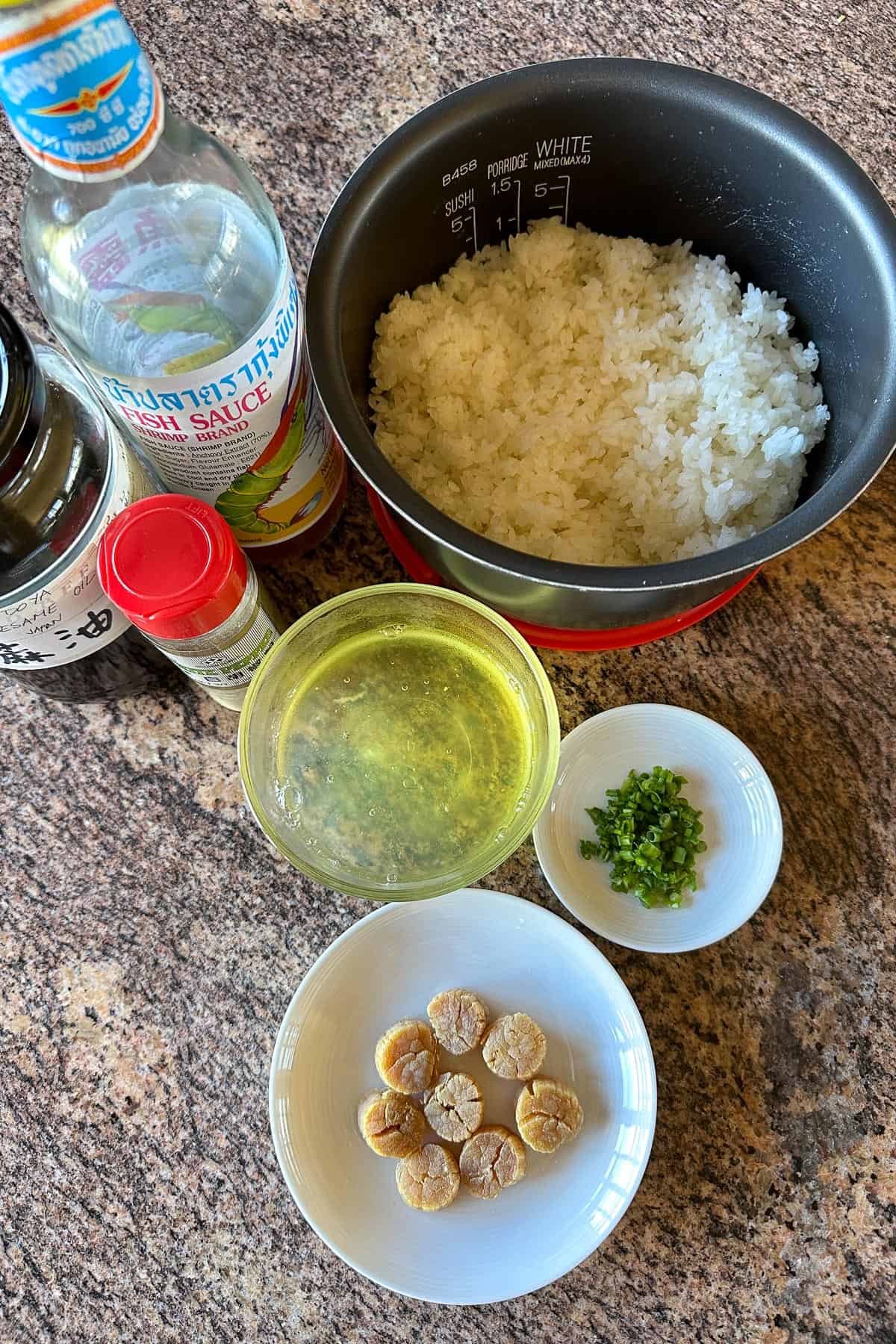 Ingredients for Dried Scallop and Egg White Fried Rice laid out on a table (rice, dried scallops, egg whites, green onions, fish sauce, sesame oil, and white pepper).