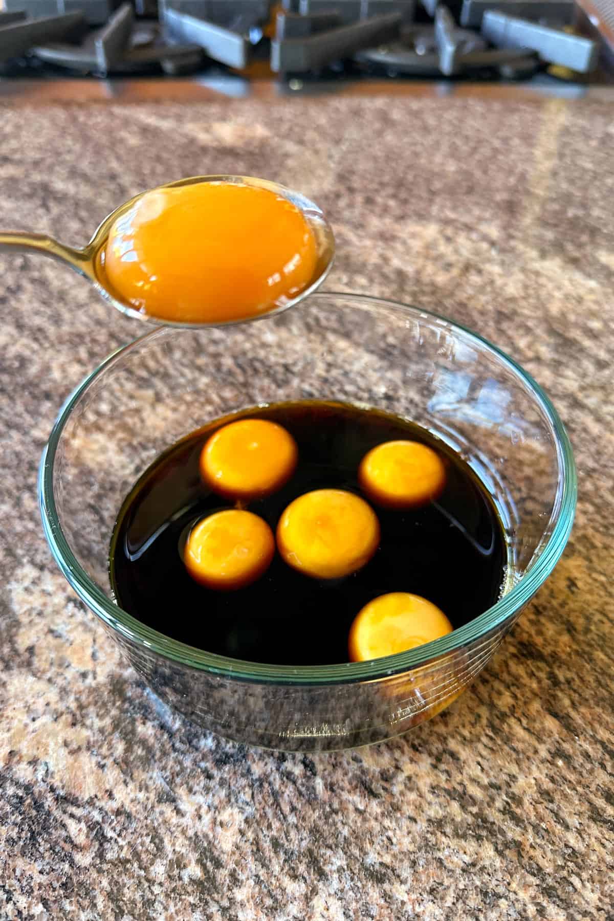 Placing eggs in the marinade for Soy Cured Egg Yolks.