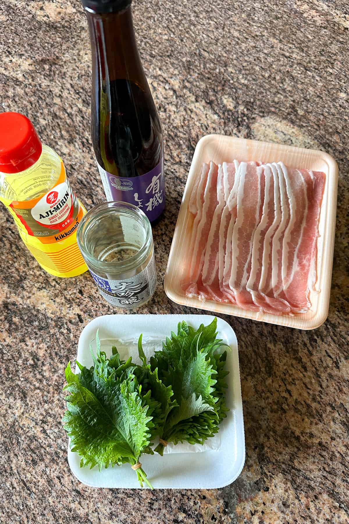 Ingredients for making Pork Shiso on a table (pork belly, shiso leaves, mirin, soy sauce, and sake).
