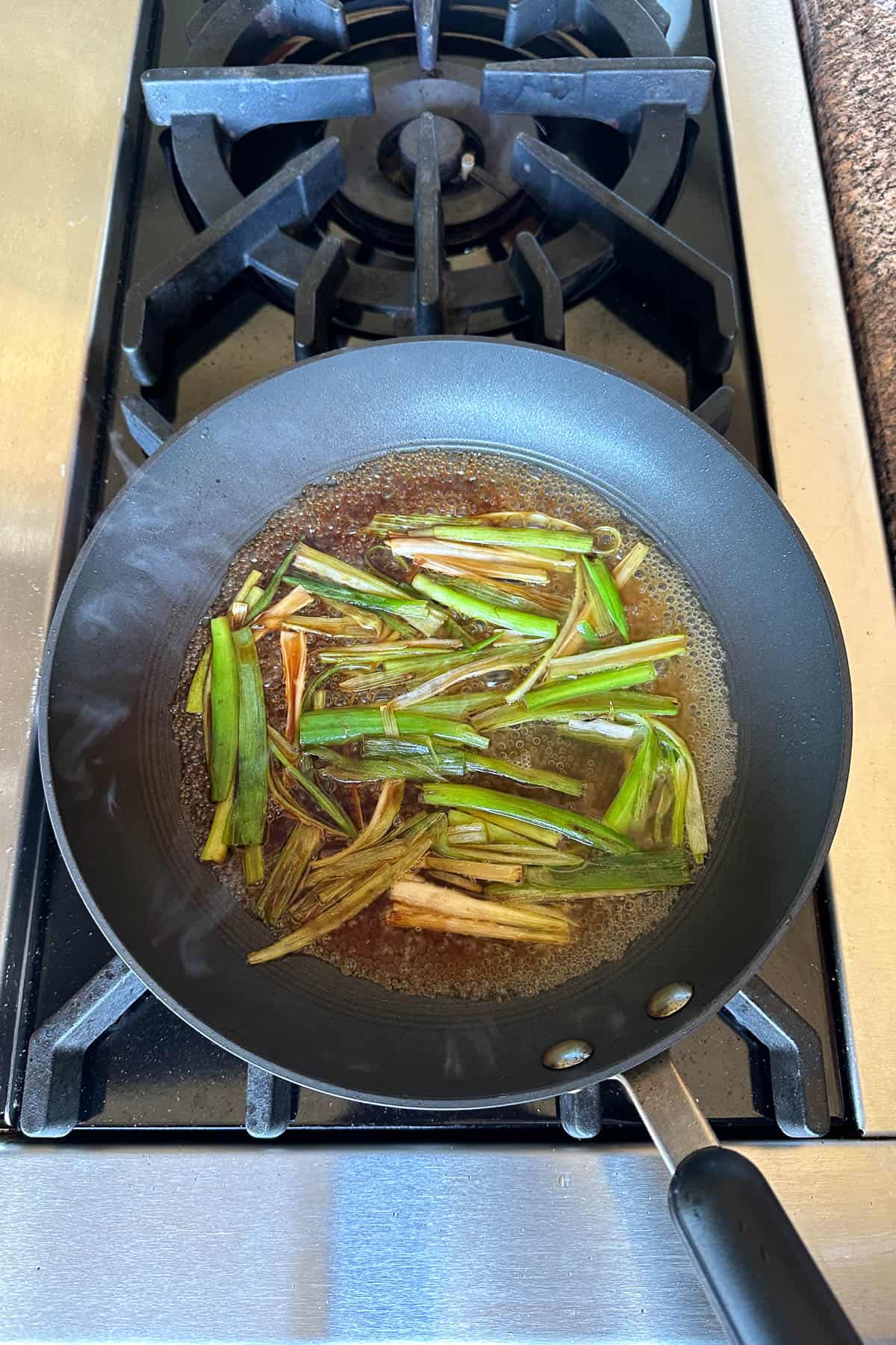 Pan frying scallions with soy sauce and chicken broth.