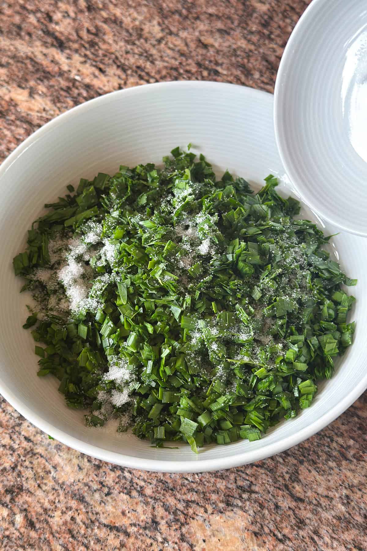 Salting chopped garlic chives.