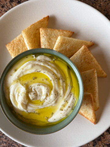 A bowl of whipped ricotta served with toast points on the side.