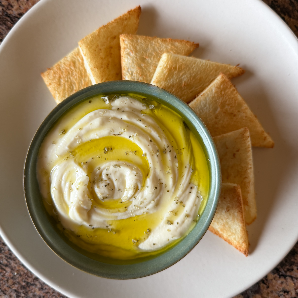 A bowl of whipped ricotta served with toast points on the side.