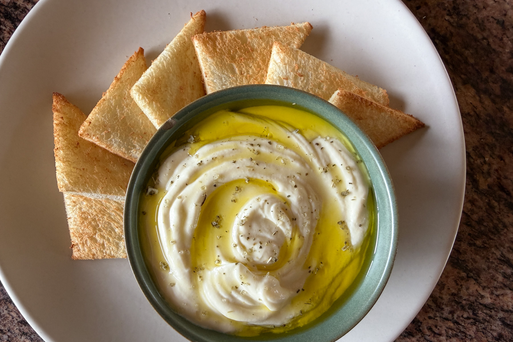A bowl of whipped ricotta served with toast points on the side.